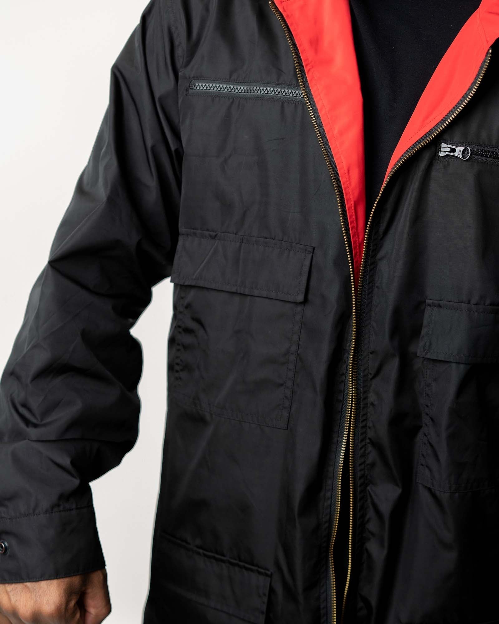 Close-up of the utility pockets and contrast red lining on the black side of the coat.