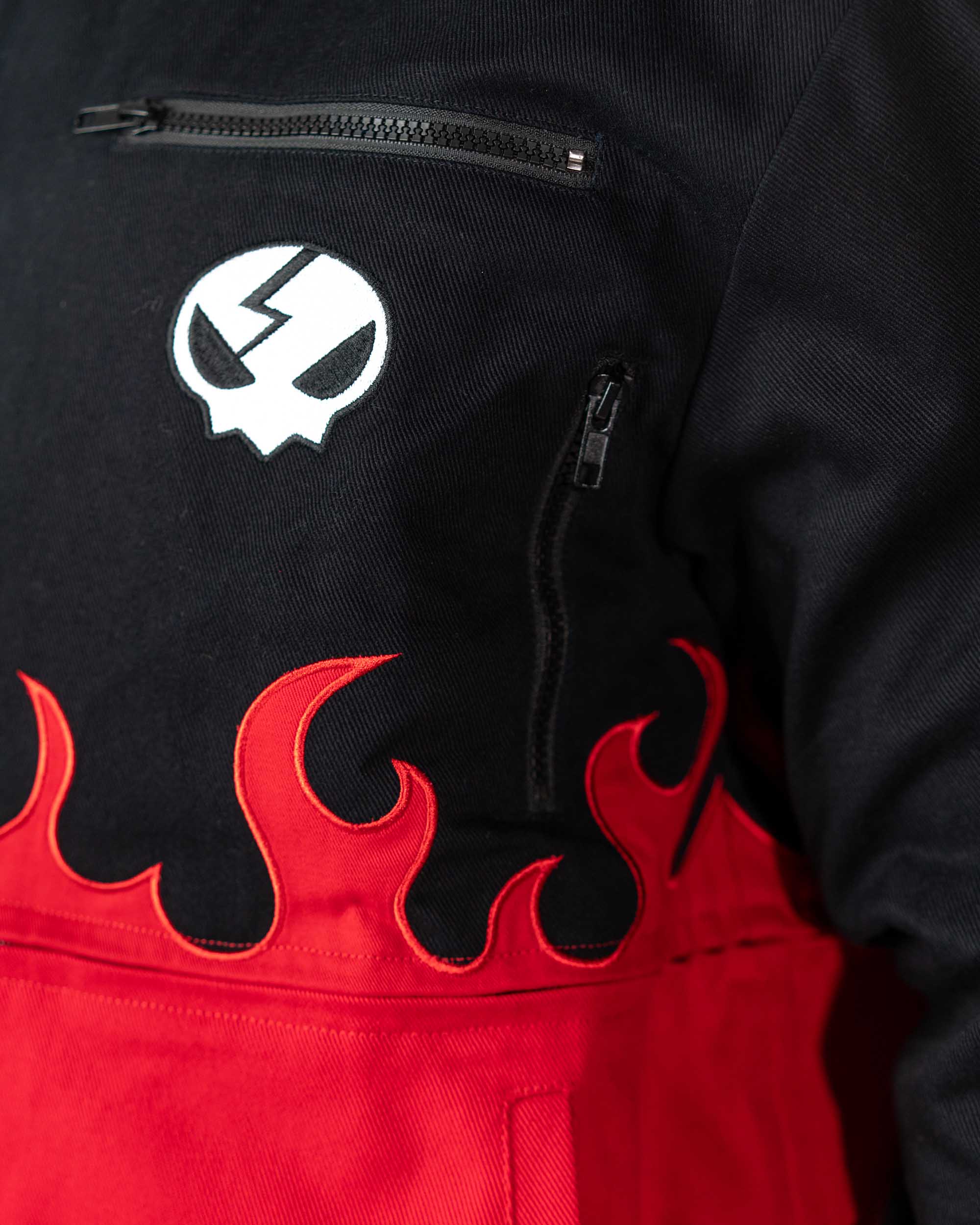 Detailed close-up of a pocket on the black Gurren Lagann jacket, showing the red flame patterns and fabric texture.