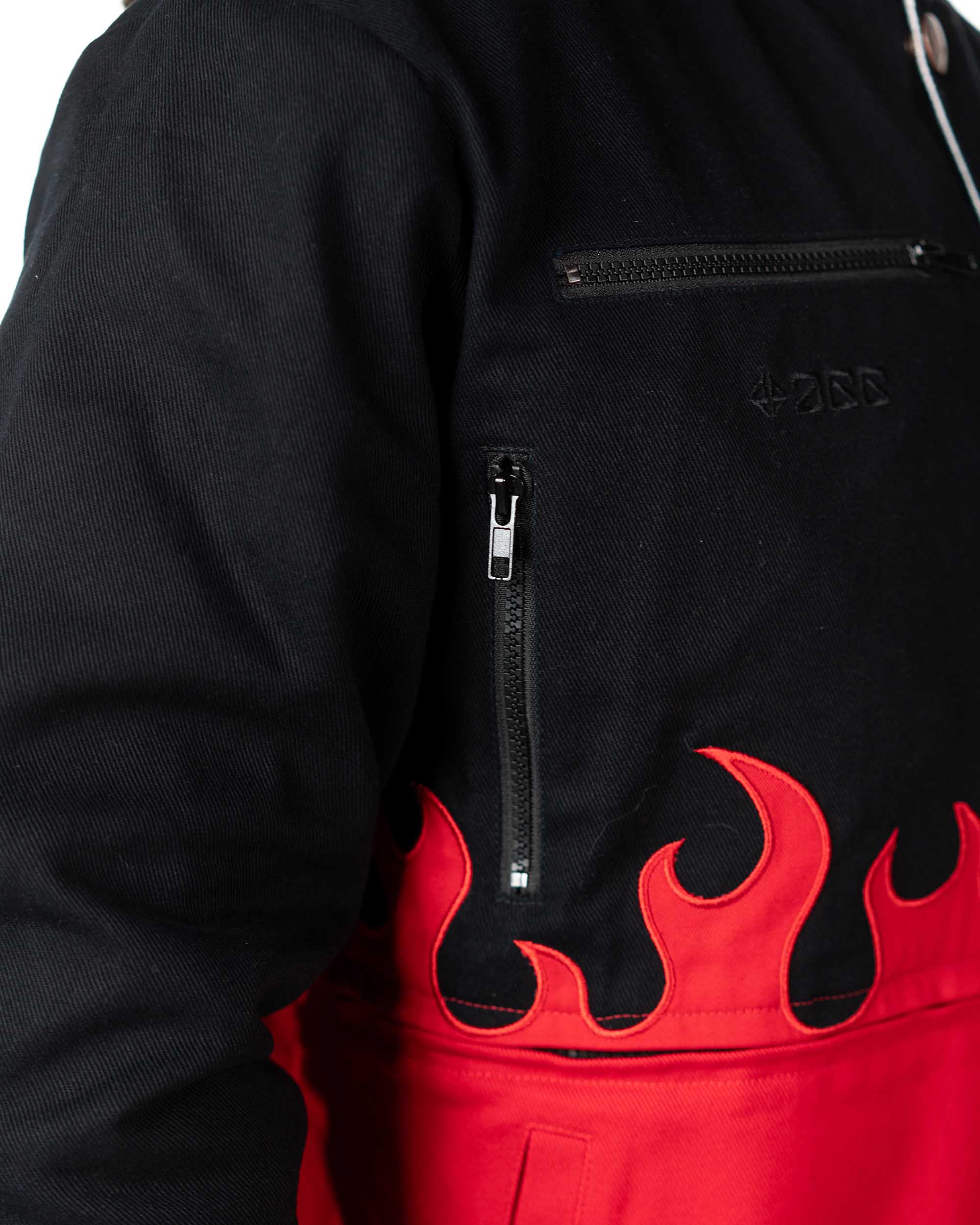 Close-up of the front lower section of the cropped black Gurren Lagann jacket on a model, showing red flames and pockets.
