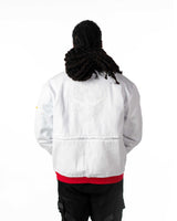 Back view of male model in cropped white Gurren Lagann jacket with hood down and red stripe details.