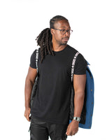 A male model wearing the Simon Gurren Lagann denim jacket showing off inner shoulder straps