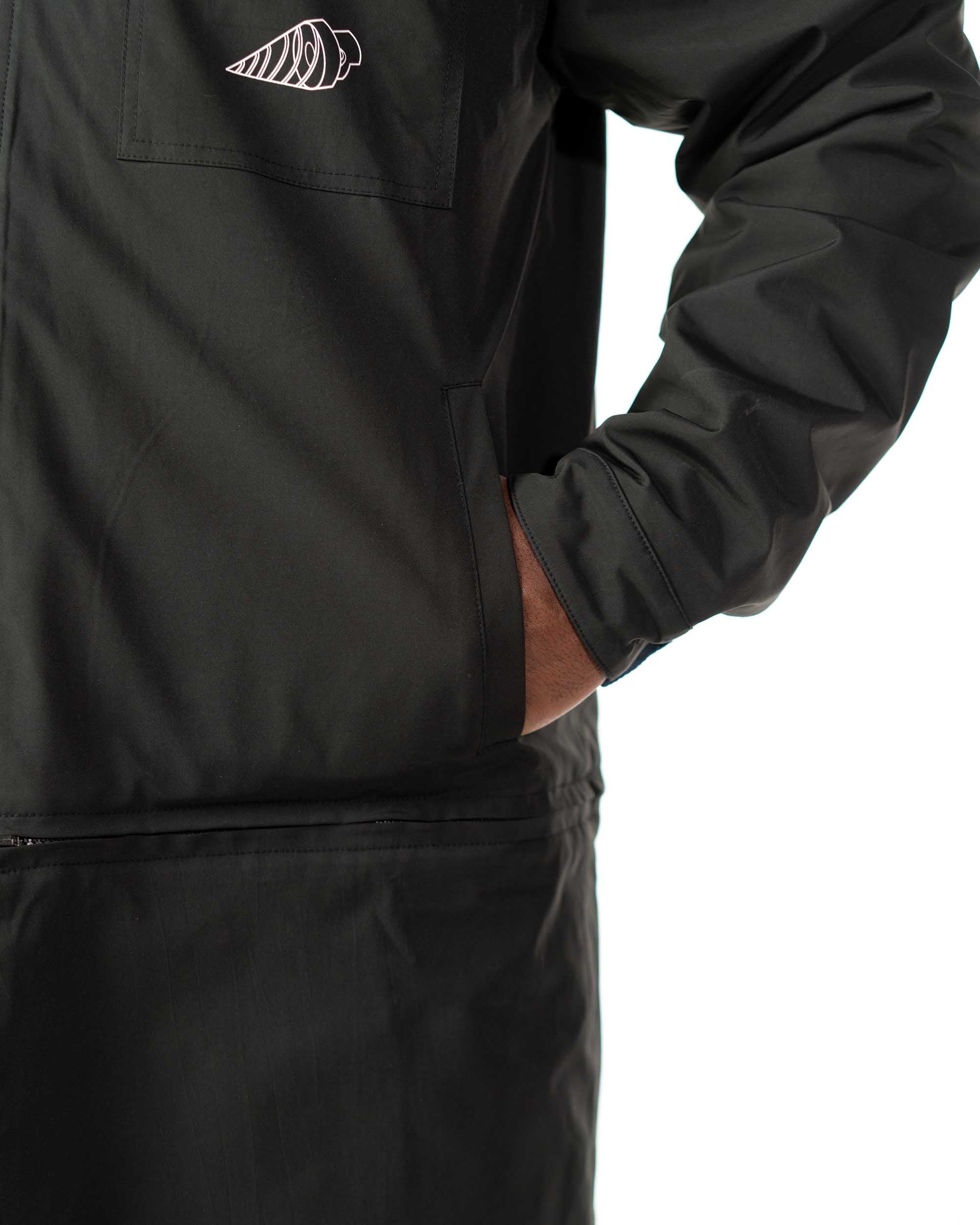 Close up of model putting a hand inside the lower seam pocket of the black polyester coat side