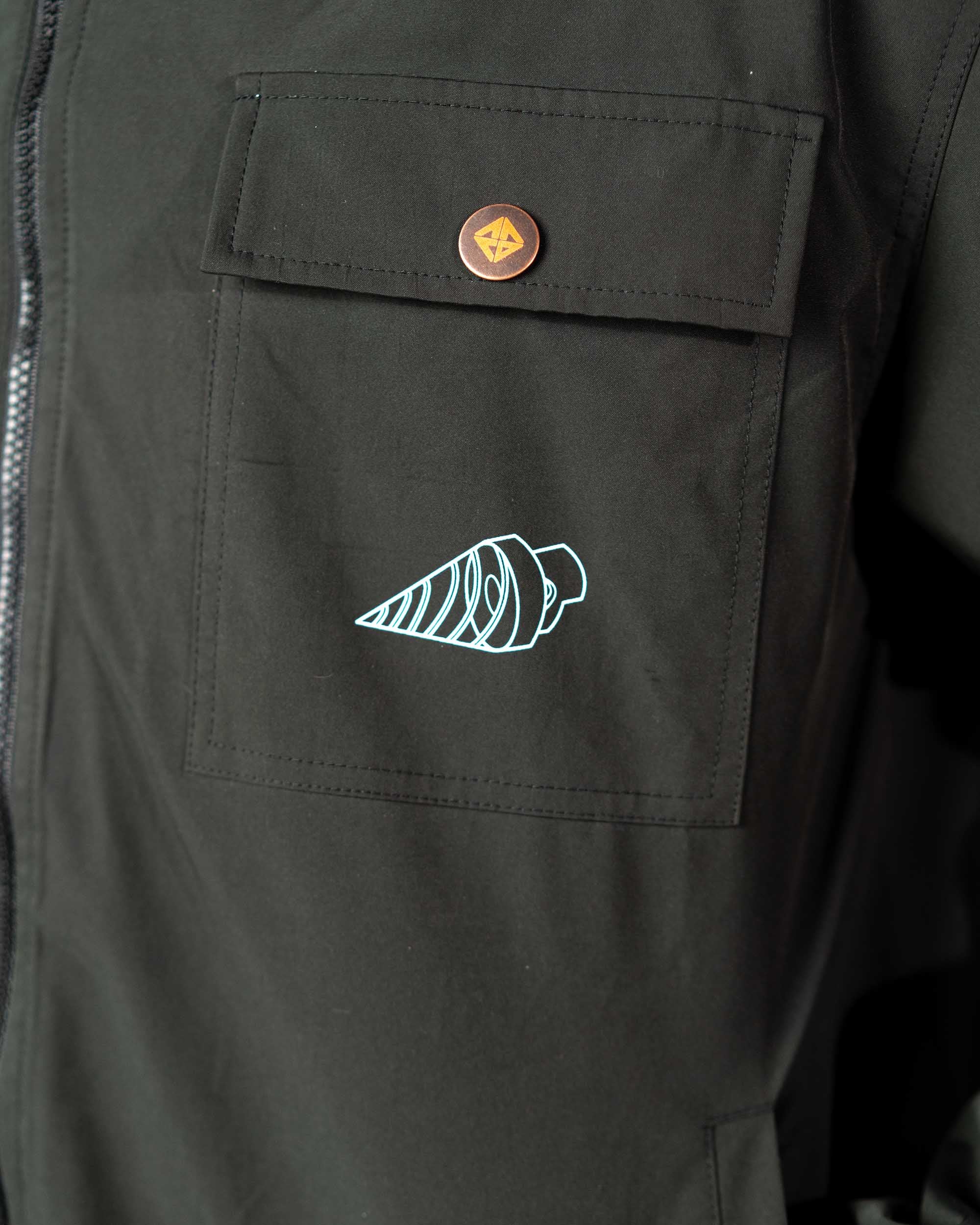 Detailed shot of the white embroidered core drill symbol on the black polyester coat's chest pocket