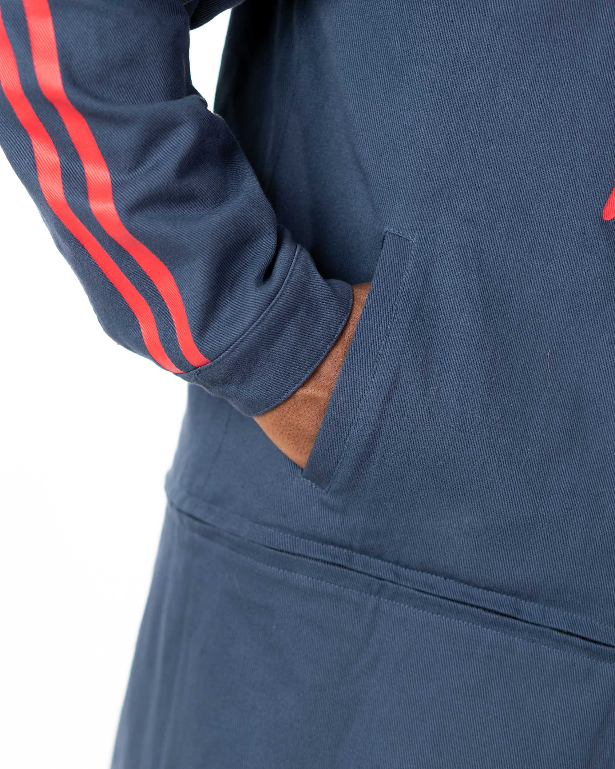 Close up of the model's hands resting in the lower seam pockets of the blue denim side