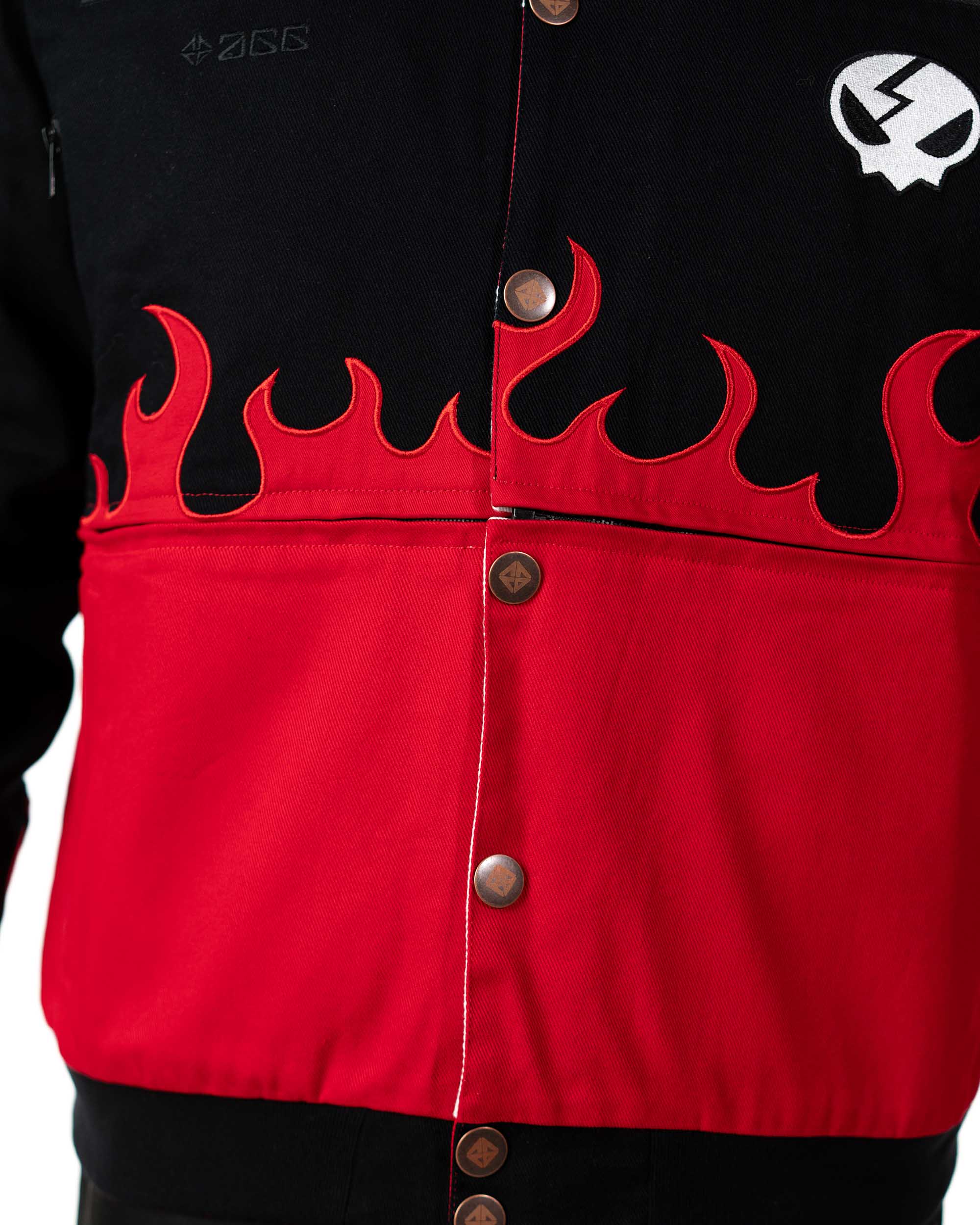 Close-up of the front lower part of the black Gurren Lagann jacket on a male model, showing red flames and small flaming skull emblem.