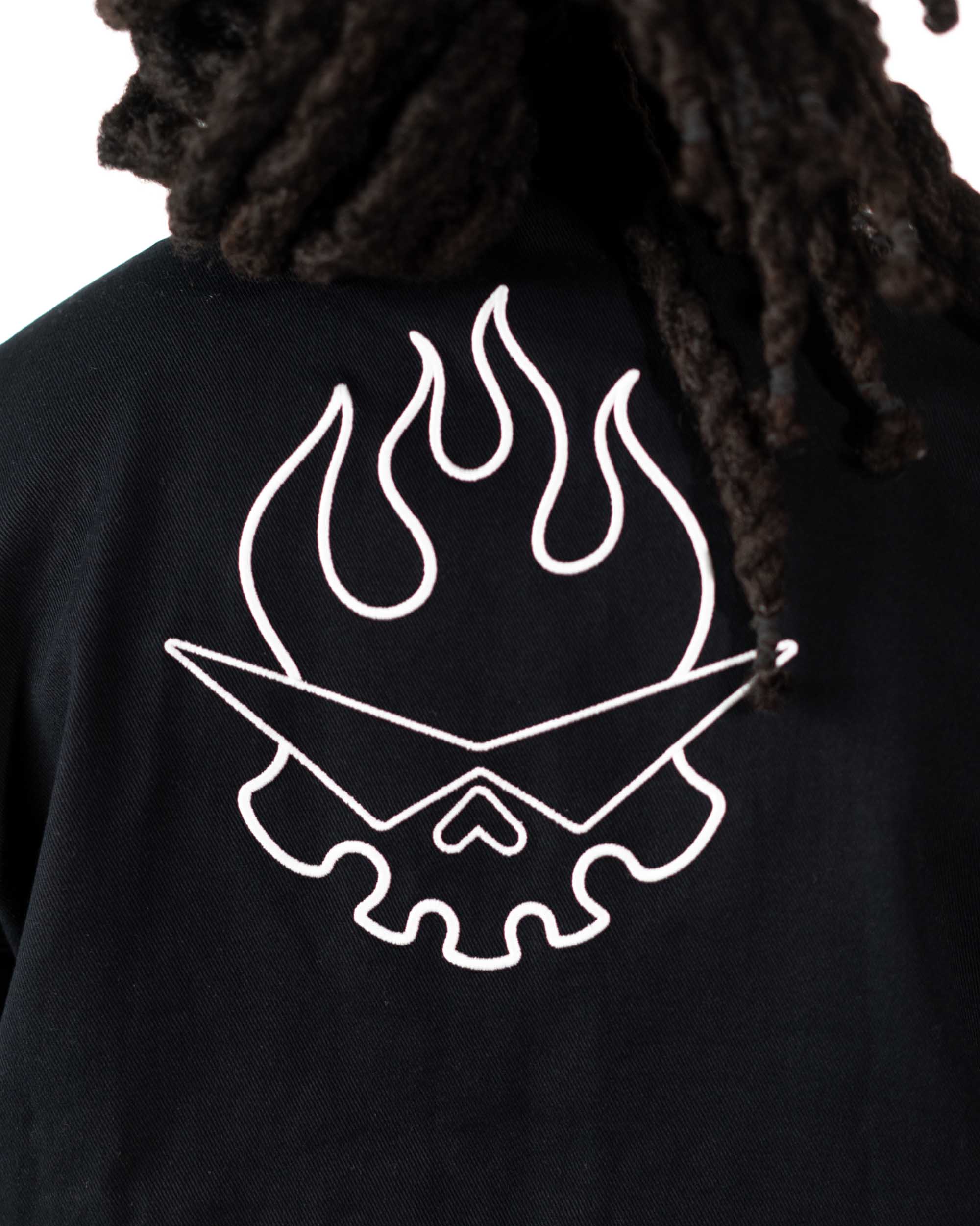 Close-up of the chest area of the black jacket featuring a functional pocket and white flaming skull print