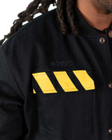 Close-up of the front chest area of the black jacket featuring yellow hazard stripe print details