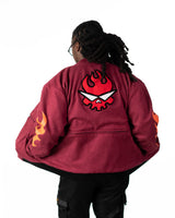 Close-up of the maroon jacket chest pocket featuring the small black embroidered flaming skull logo