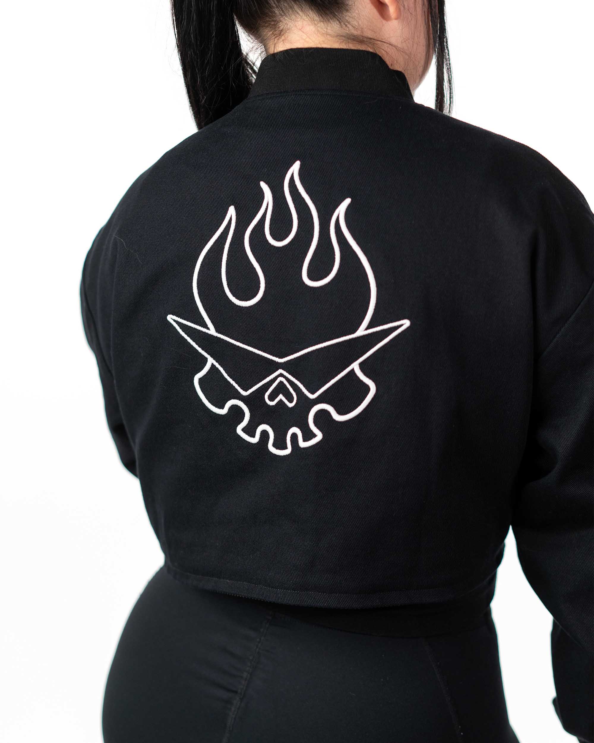 Detailed back view of the cropped black jacket on a model showcasing the white Team Dai Gurren skull embroidery