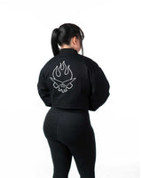 Back view of female model in the cropped black jacket featuring the white-stitched flaming skull embroidery