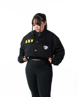 Front view of female model wearing the cropped black side of the reversible jacket with yellow stripe detail