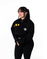 Lifestyle shot of female model in the cropped black jacket with yellow stripes looking aside