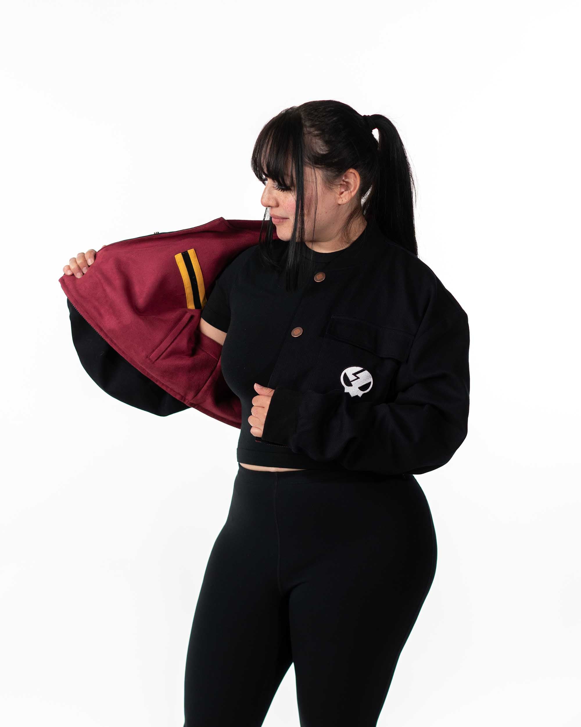 Female model wearing the cropped black jacket open to reveal the reversible maroon interior layer