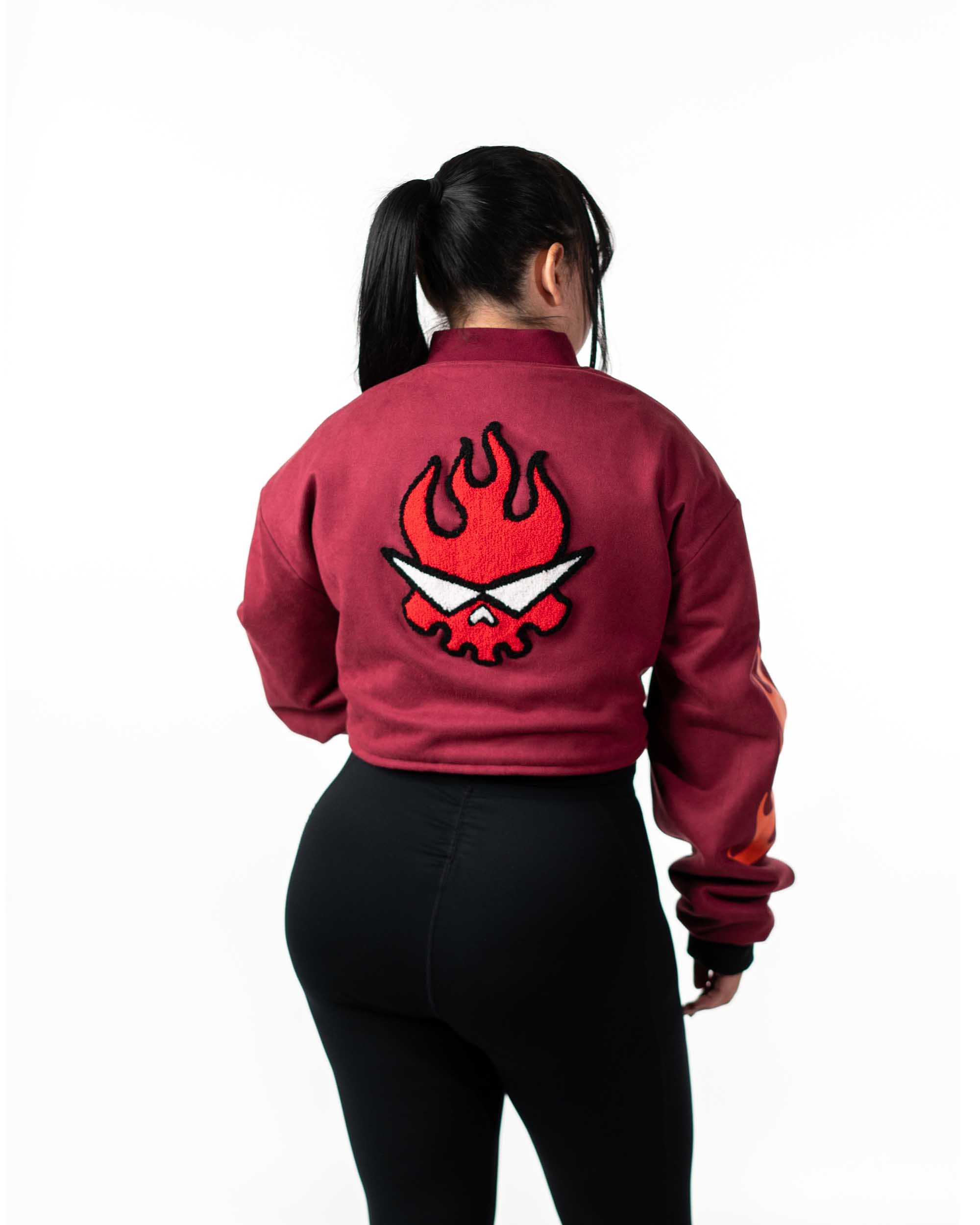 Full back view of female model wearing the cropped maroon jacket with red and orange flaming skull graphic