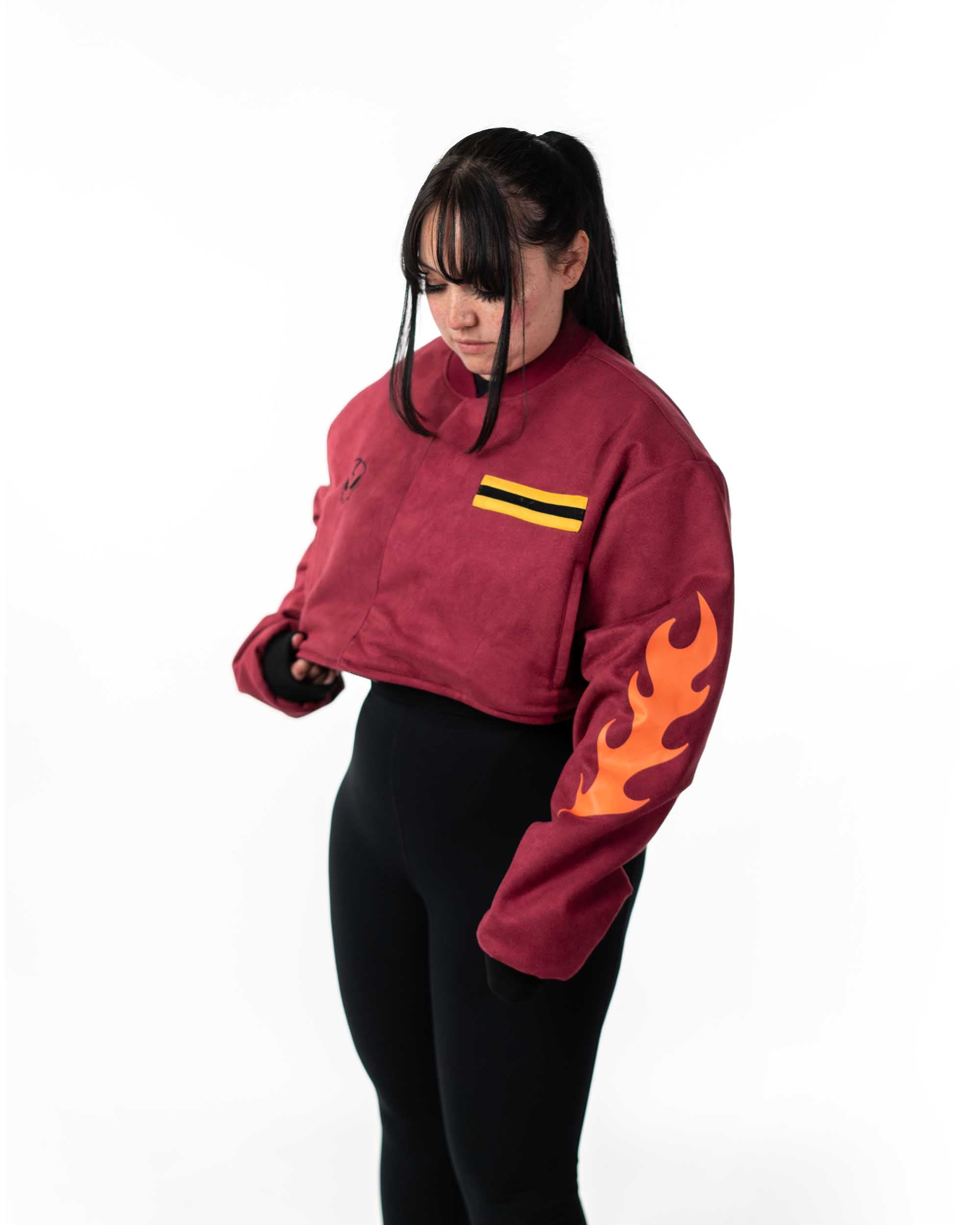 Front view of female model wearing the cropped maroon side of the reversible jacket with yellow chest stripes