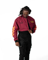 Front view of male model standing in full length maroon side of the reversible jacket with orange flame sleeve
