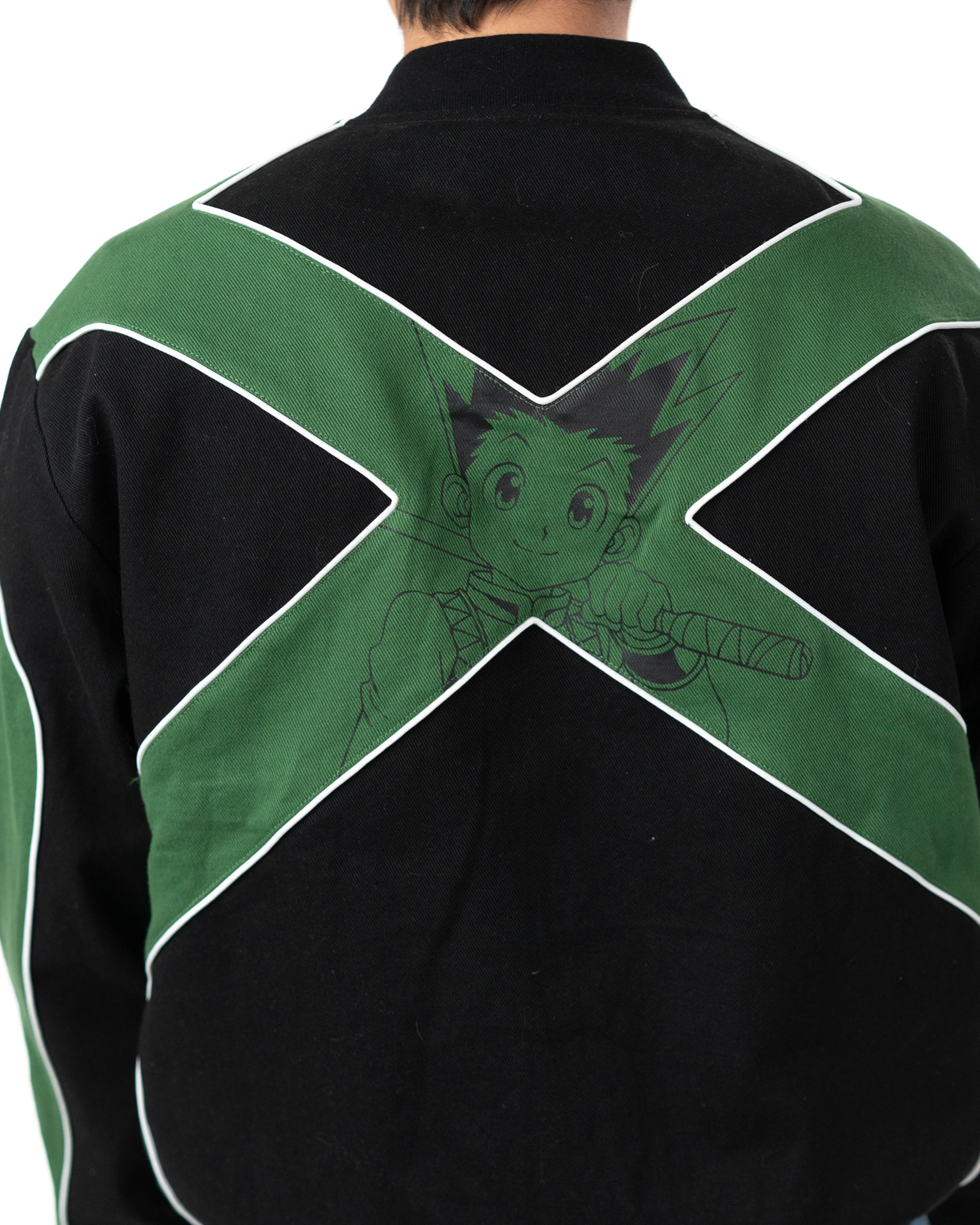 Back view of the Gon racing jacket showing the large green X graphic with a faint print of Gon Freecss