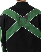 Back view of the Gon racing jacket showing the large green X graphic with a faint print of Gon Freecss