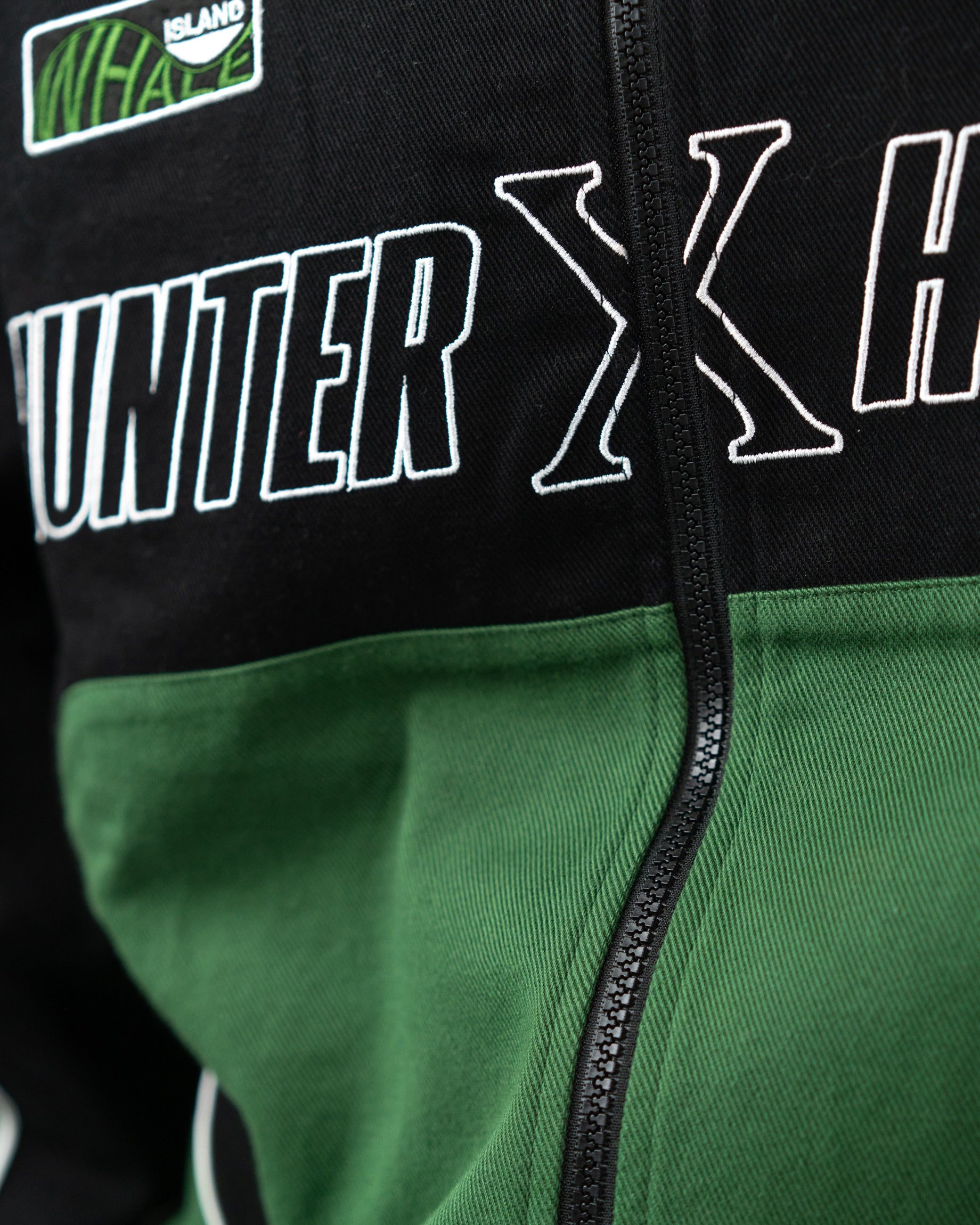 Detailed close up of the front zipper and bold Hunter x Hunter lettering across the green panel