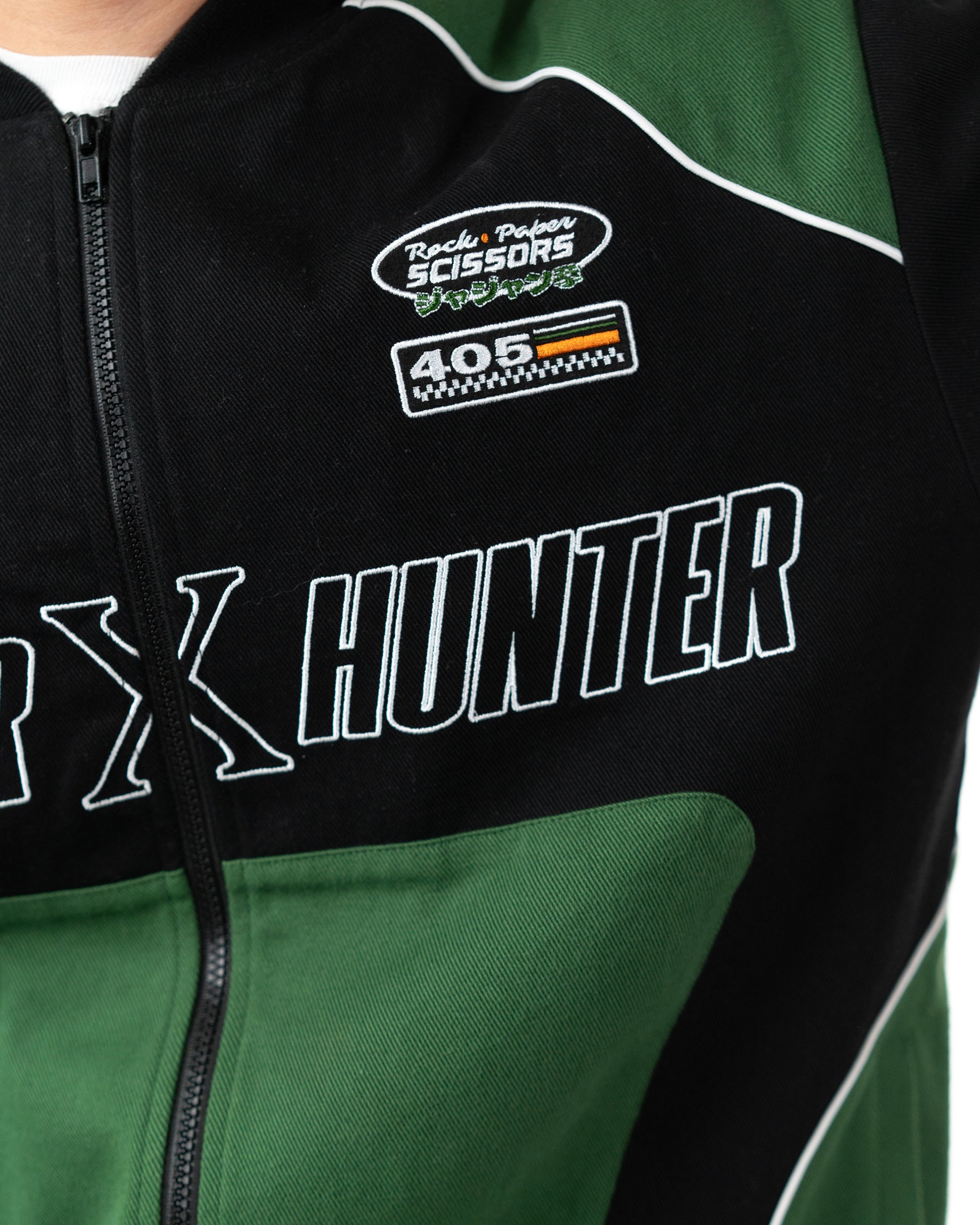 Close up of the left side chest of the green and black Gon racing jacket highlighting the embroidered patch details