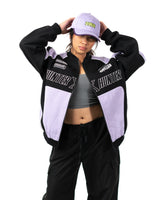 Female model posing in the lavender and black Killua racing jacket with hands on her baseball cap