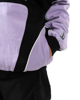 Close up of the side slash pocket on the lavender and black Killua racing jacket with hand in pocket