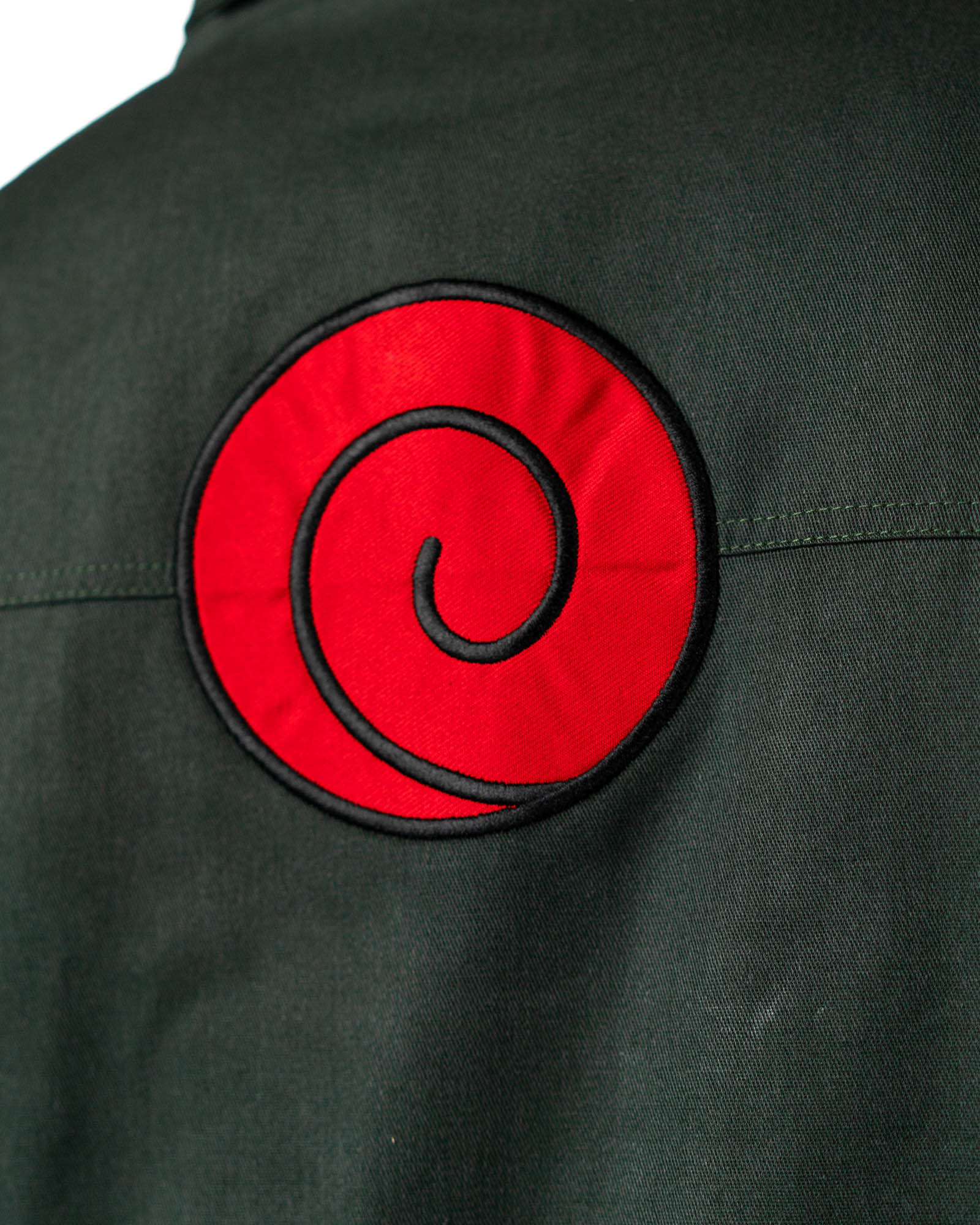 Naruto Shippuden Jonin Jacket back close-up featuring the large embroidered red Uzumaki spiral patch on dark green fabric