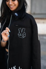 Detail shot of the white Shinigami peace sign hand gesture embroidered on the chest