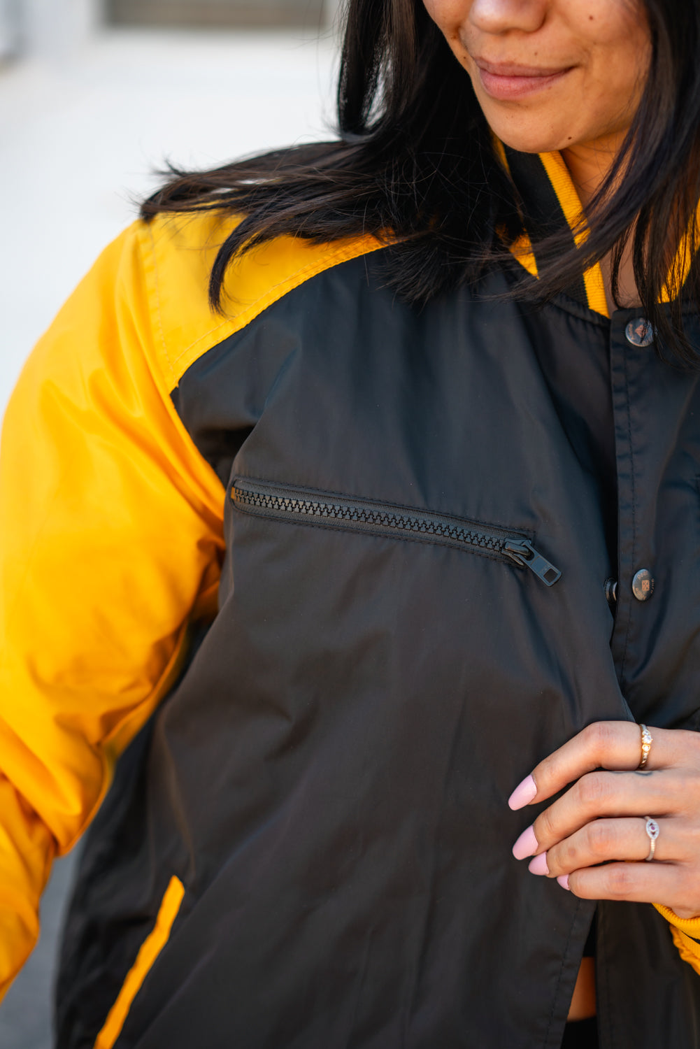 Close-up of the jacket collar and black snap-button front with yellow sleeves.